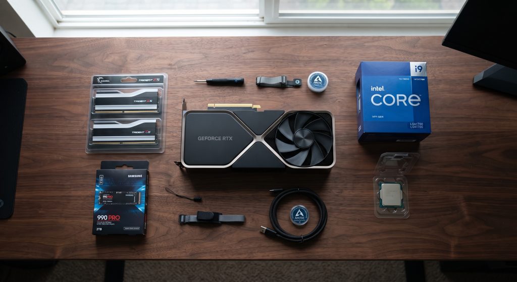 Custom gaming PC build components laid out on a clean workbench, including a graphics card, RAM, and CPU.